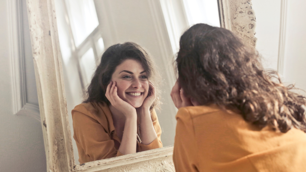 woman smiles at her own reflection